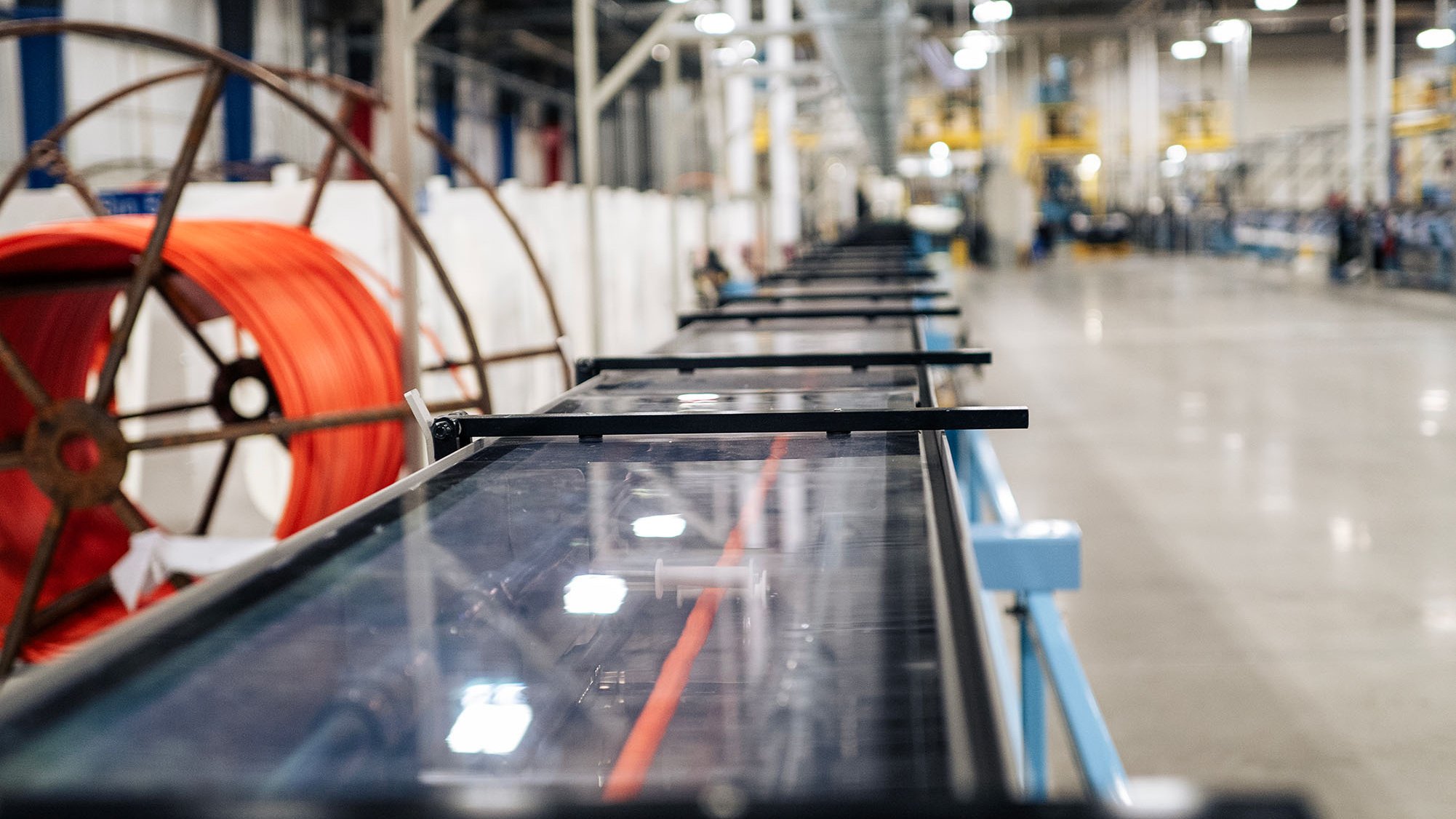 A production line producing microduct in a well-lit factory hall. You can see an orange microduct in the cooling bath.