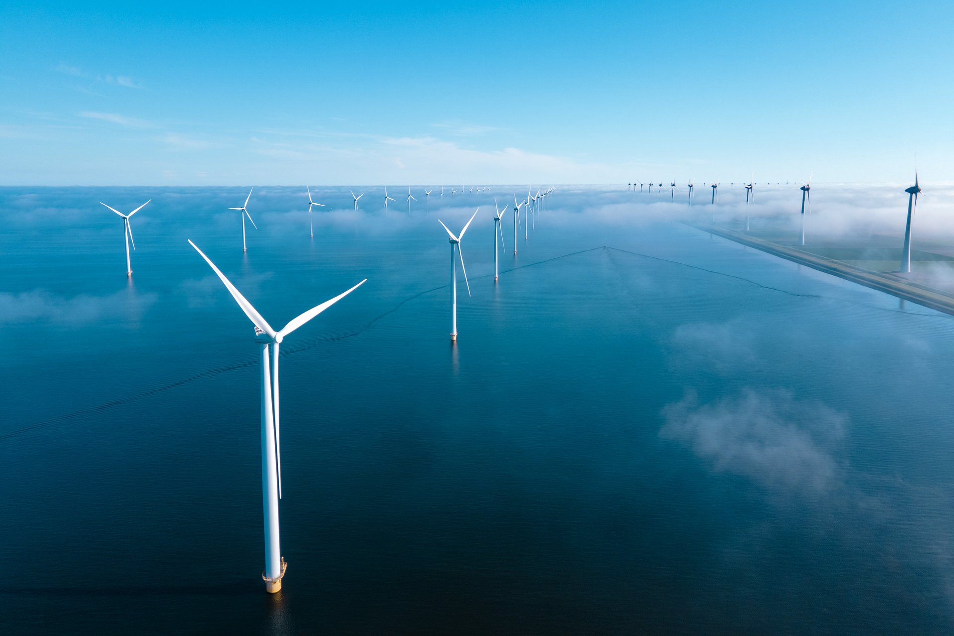 Offshore wind turbines with coastal landscape in the distance