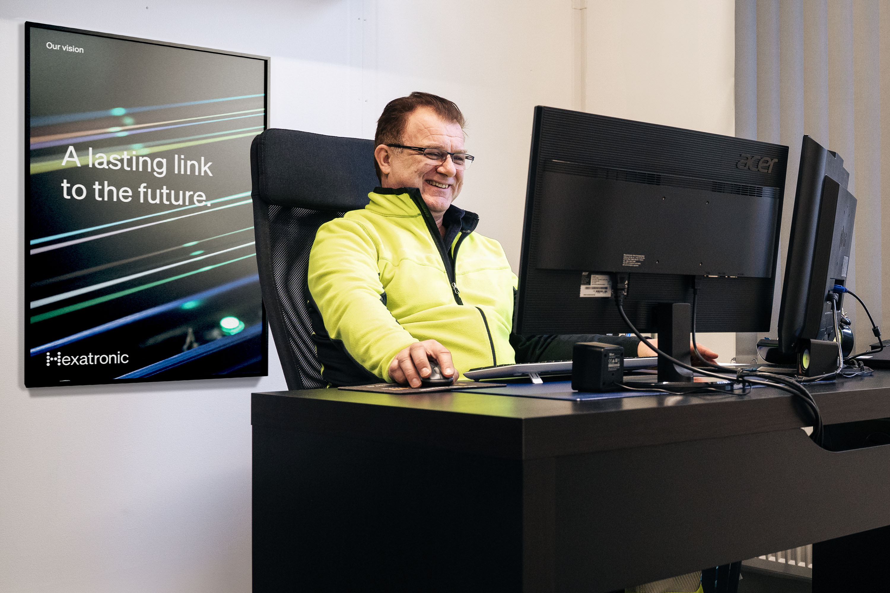 A person sits and works with a computer at a desk in a modern office.