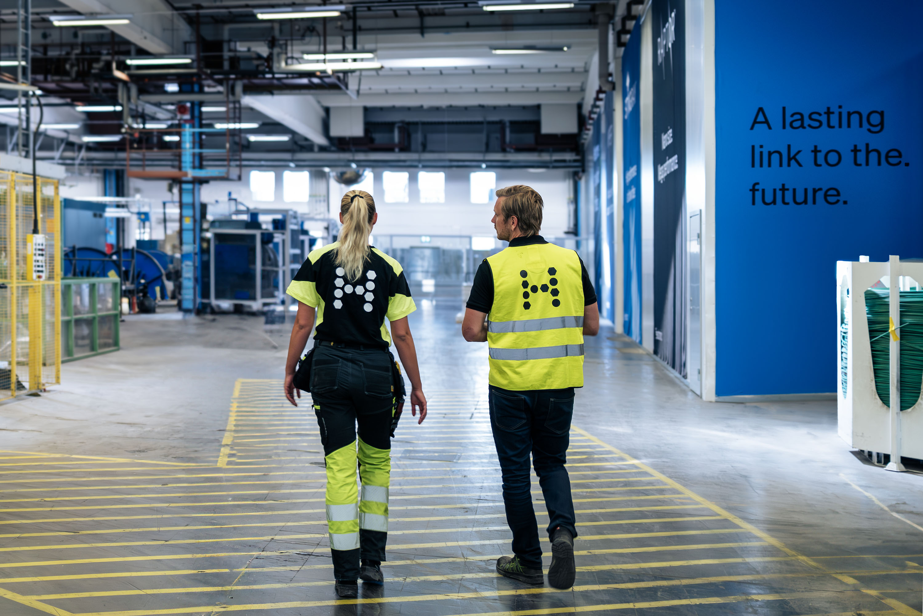 Two Hexatronic employees are walking inside the factory in Hudiksvall, Sweden.