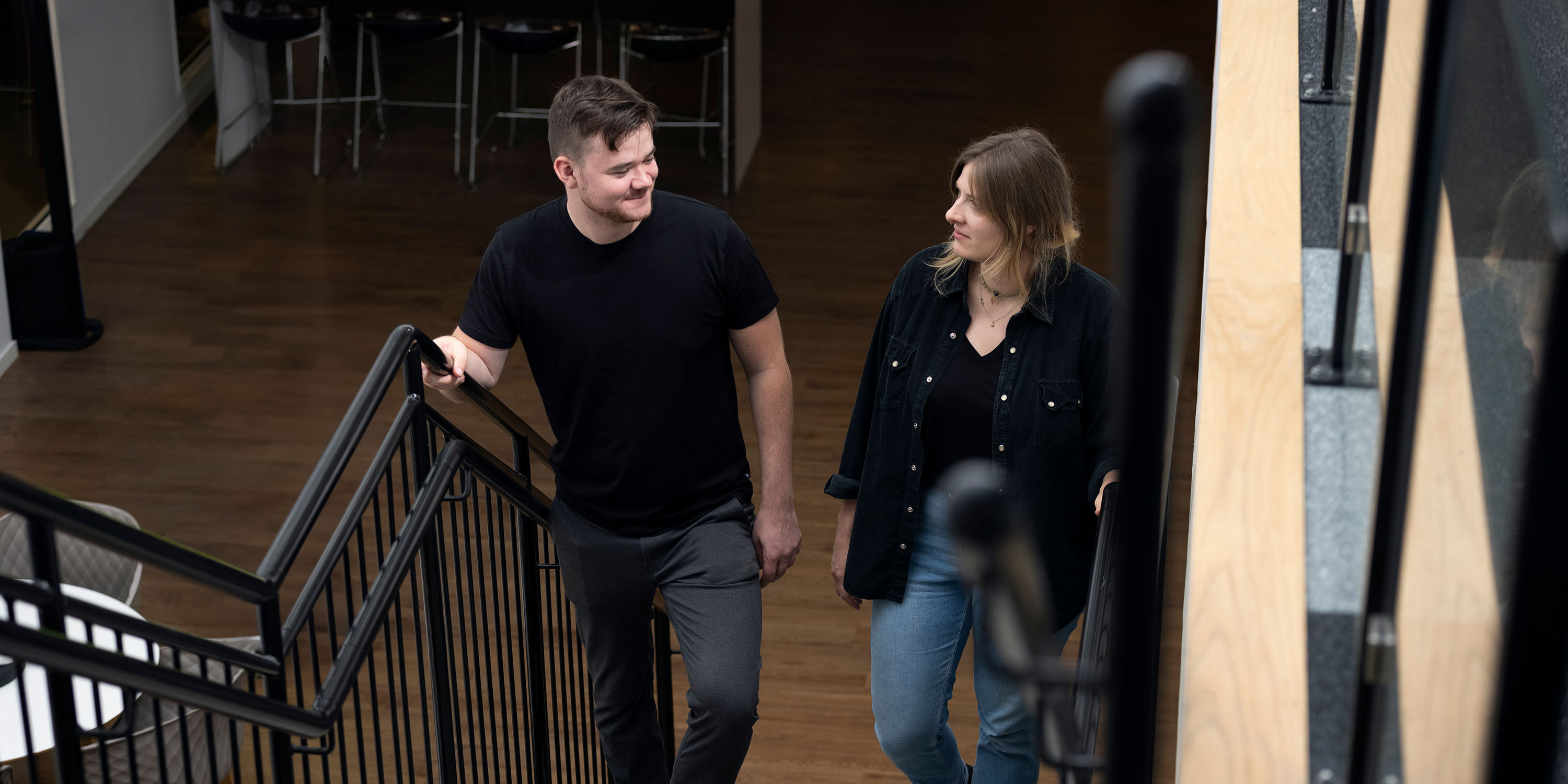 Two people on their way up a flight of stairs indoors in an office.