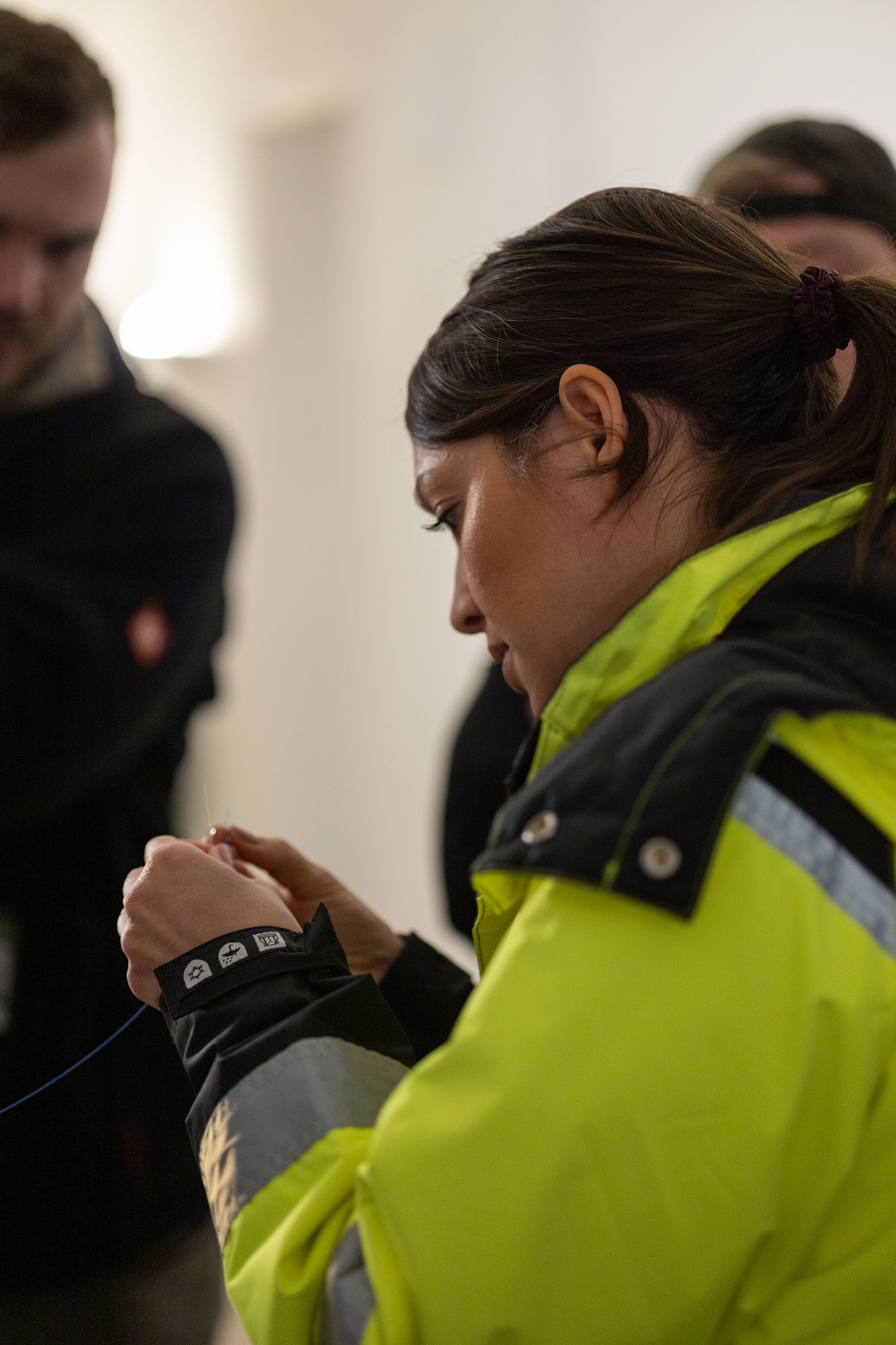 Close-up on a person in a high visibility jacket holding a thin fiber optic cable.