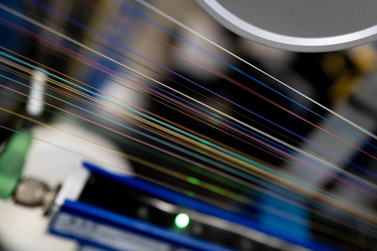 Colorful fibers aligned and processed through machinery.