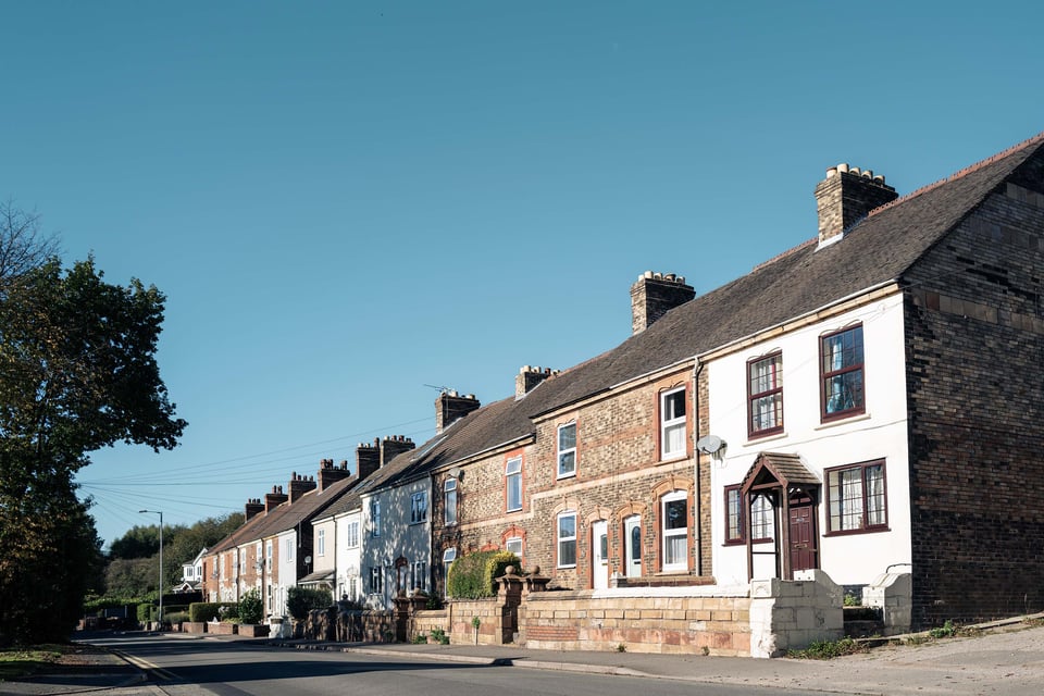 A peaceful street with unique, closely packed houses under a clear sky, evoking a sense of community and tranquility.