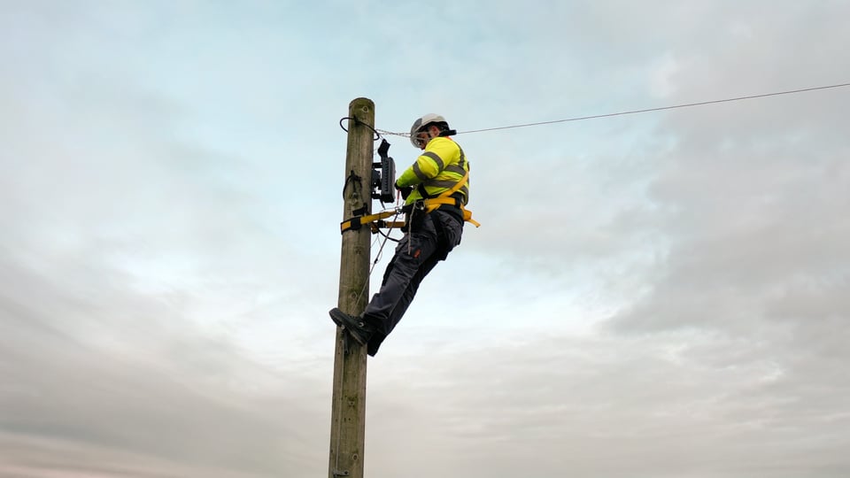 Fiber technician mounting aerial fiber connection on a pole. 